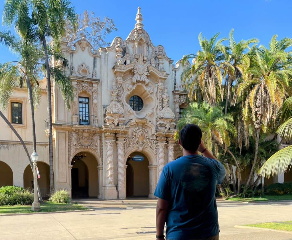 The museums at Balboa Park, Person looking at architecture and palm trees.