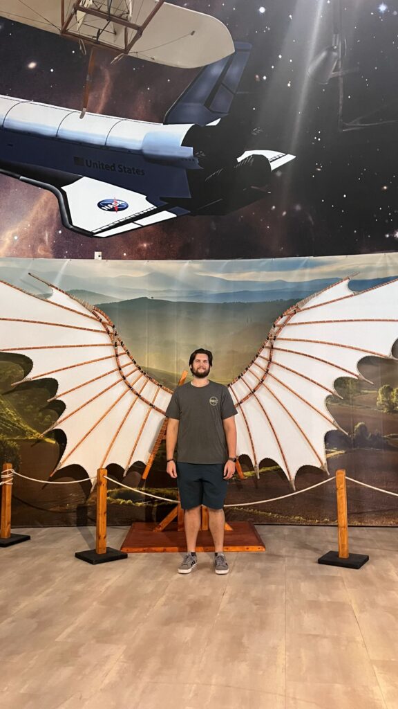 Man standing in front of leonardo davincei wings at the exhibit in air and Space Museum in san diego.